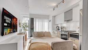 A modern bedroom with a large bed, a bedside table, and a TV displaying a Netflix show. - StayToronto - Work-Friendly 1BR Suite Steps to Eaton Centre (Toronto)
