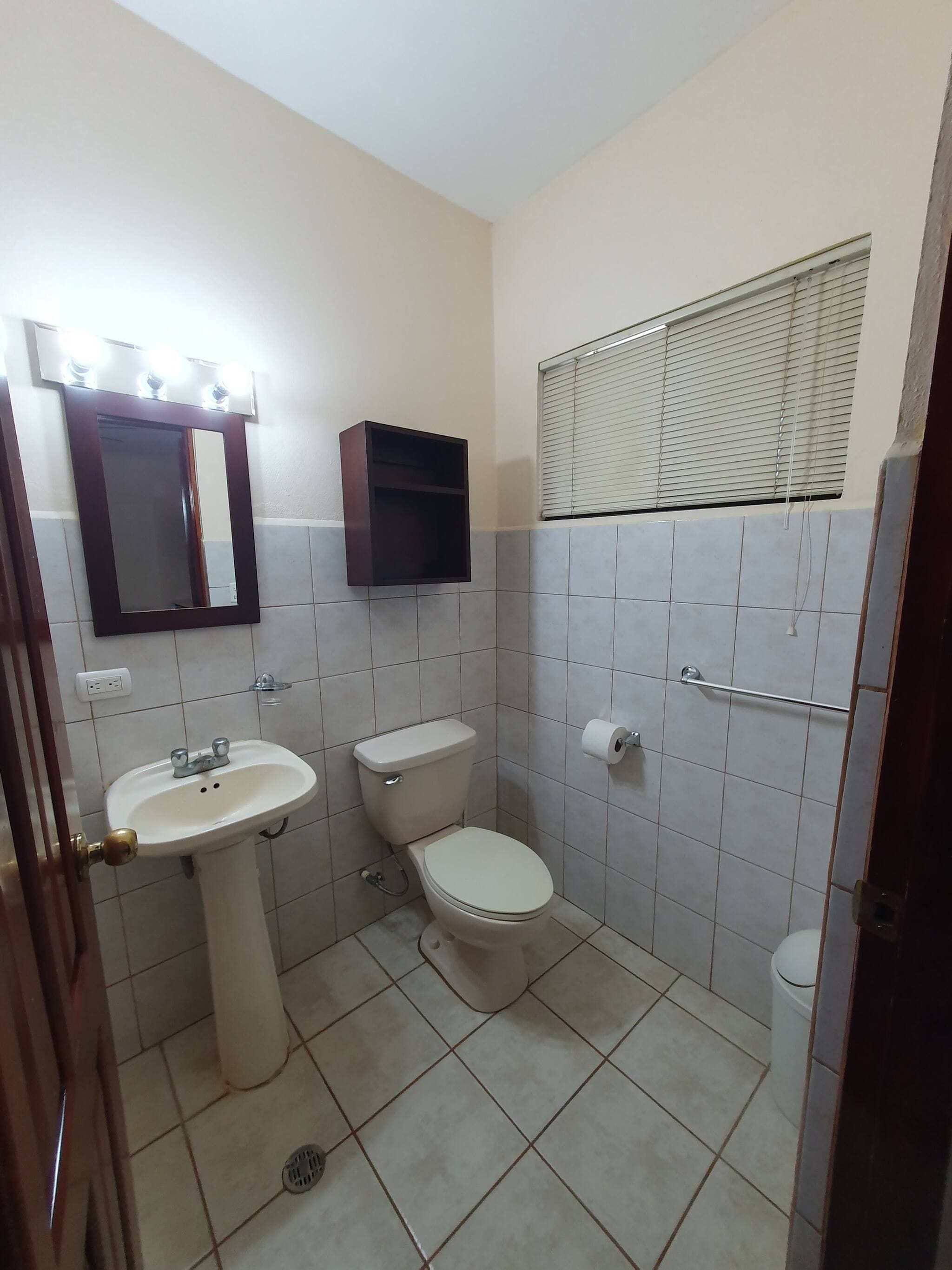 A bathroom with a sink, toilet, and mirror.