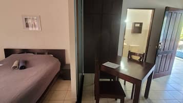 Una habitación de hotel con una cama, un escritorio y un baño visible a través de una puerta abierta.