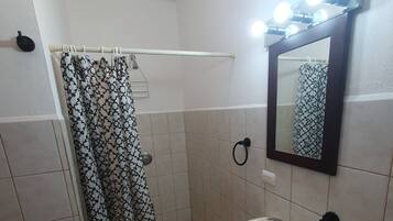 A bathroom with a shower, a sink, and a mirror with lights.