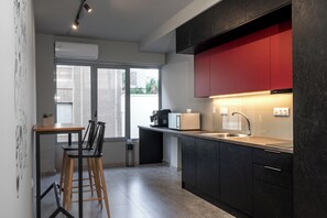 A modern kitchen with a built-in oven, a coffee machine, and a red cabinet. - Psiri Vibes Rooms & Suites in Athens (Athina)