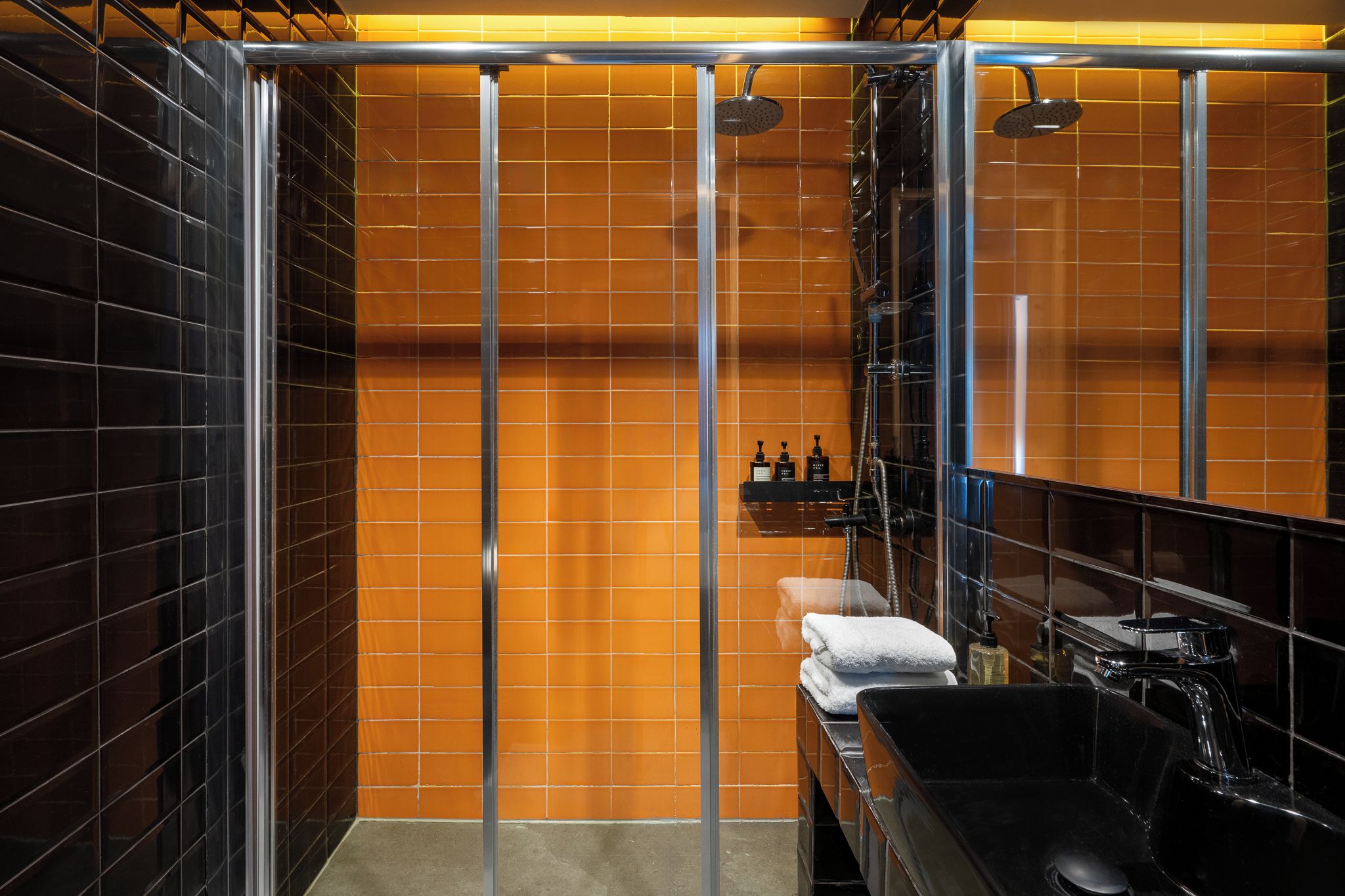 Une salle de bain moderne avec une douche à parois de verre, un lavabo noir et un porte-serviettes.