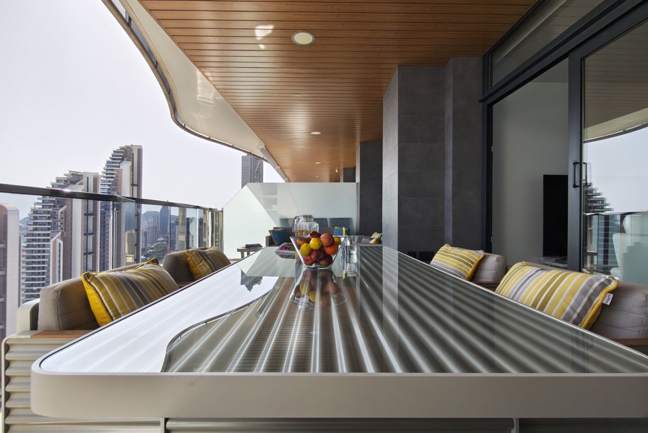 A modern dining area with a glass table, cushioned seating, and a city view.