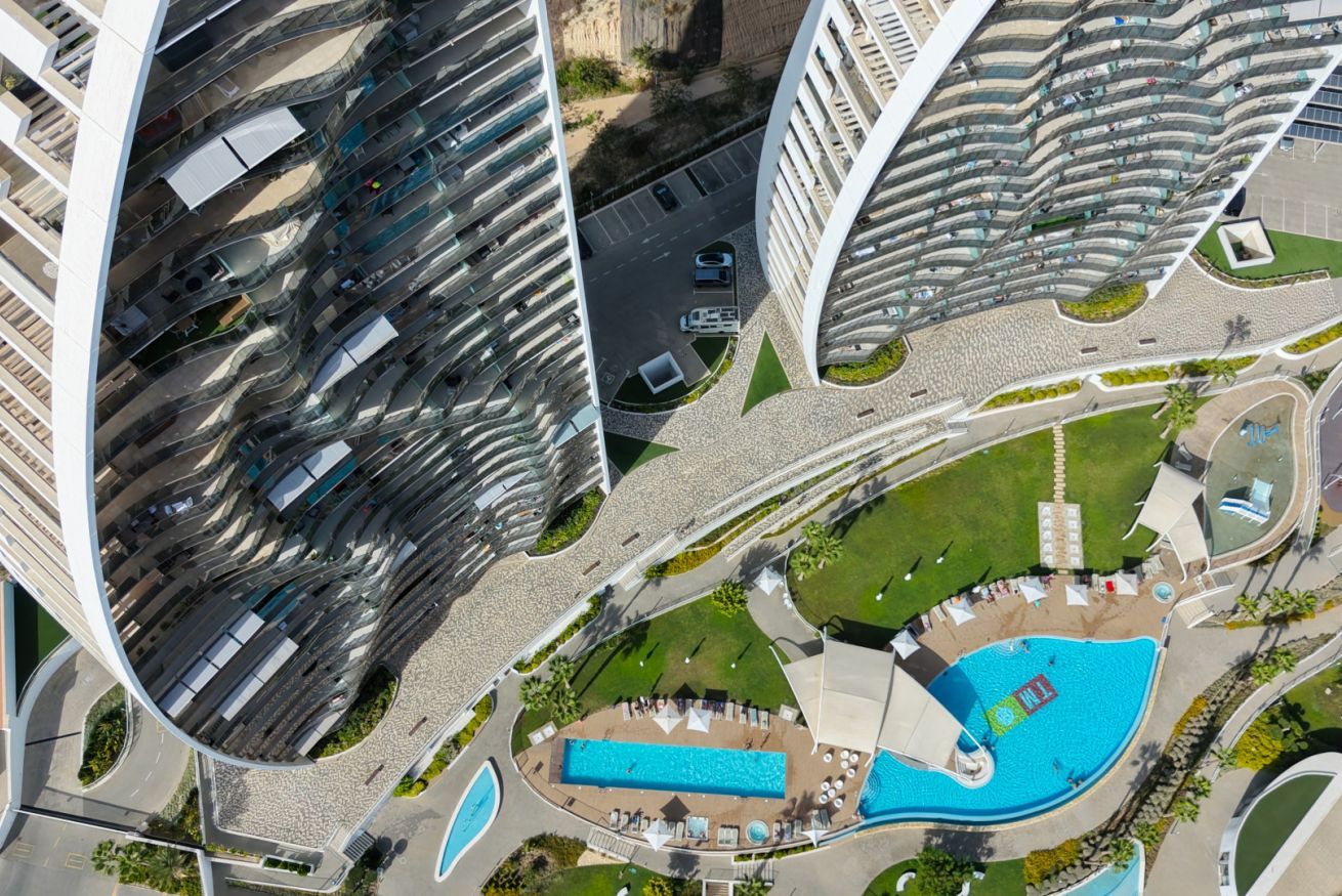 Un edificio moderno con varios balcones, piscina y zonas ajardinadas.
