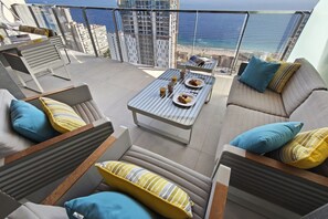 A balcony with a sofa, chairs, and a table with breakfast items. - SUNSET WAVES elegant apartment (Benidorm)