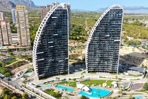 A modern hotel with two curved towers, a central pool area, and a landscaped courtyard. - SUNSET WAVES elegant apartment (Benidorm)