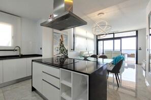 A modern kitchen with a central island, a dining area with a view, and a large window. - SUNSET WAVES elegant apartment (Benidorm)