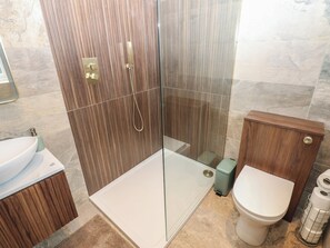 A modern bathroom with a glass-enclosed shower, a white sink, and a toilet. - Corner House (Hexham)