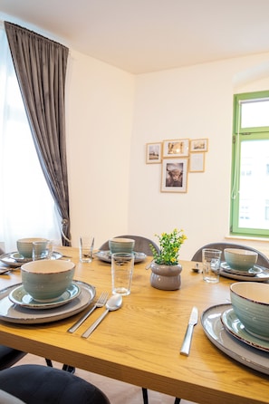 A dining table set with plates, bowls, cutlery, and glasses, with a potted plant in the center.