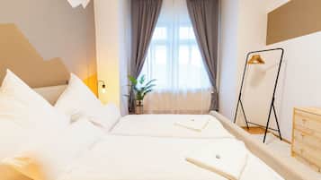 Ein Hotelzimmer mit Bett, Nachttisch, Pendelleuchte, Topfpflanze und Kleiderhaken.