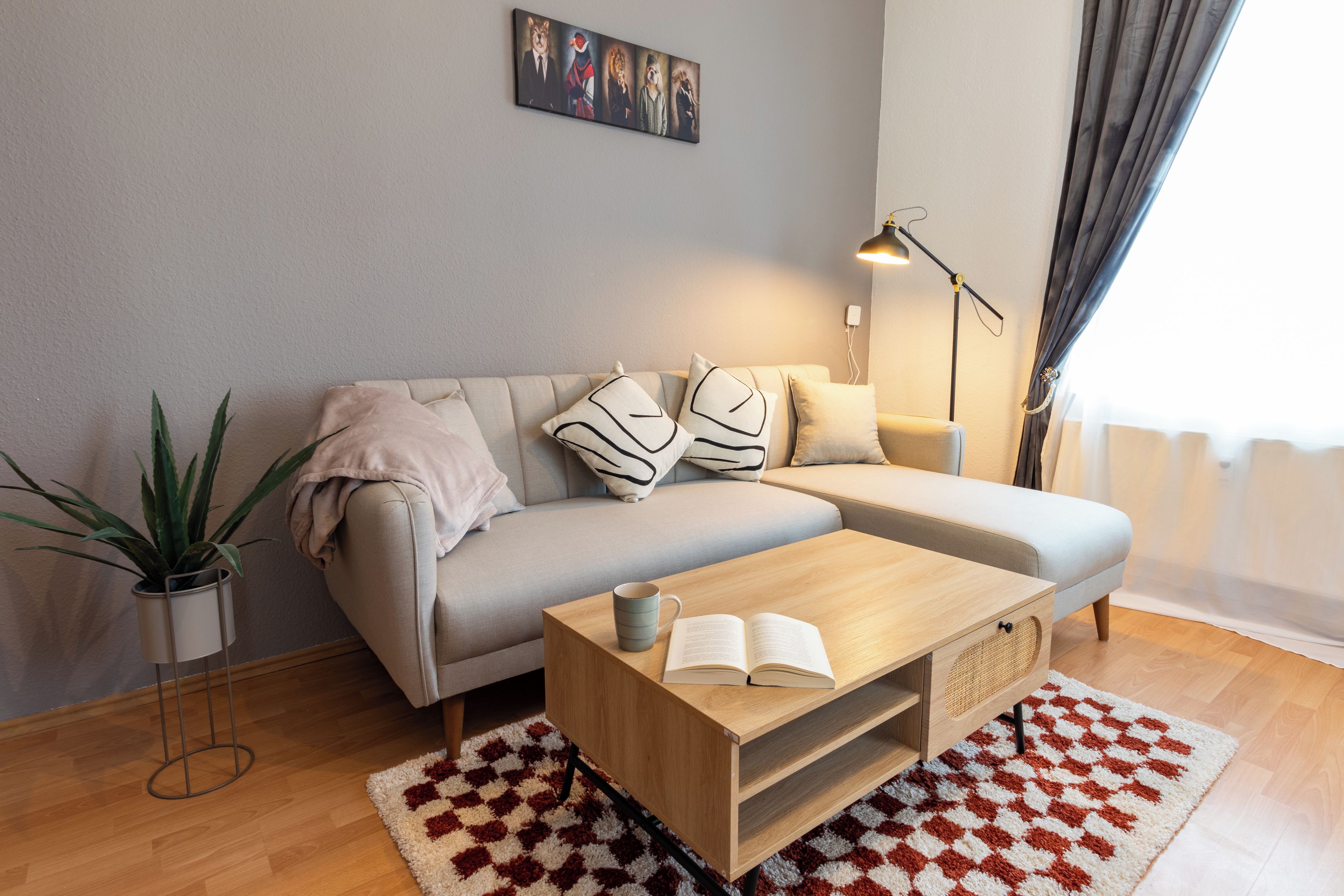 Un salon moderne avec un canapé, une table basse, un lampadaire et une plante en pot.