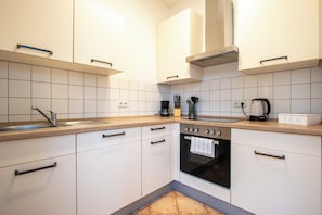 A modern kitchen with white cabinets, a stainless steel sink, a built-in oven, and a coffee maker on the countertop.