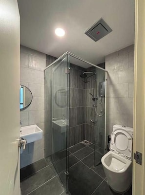 A bathroom with a glass-enclosed shower, a white sink, and a toilet.