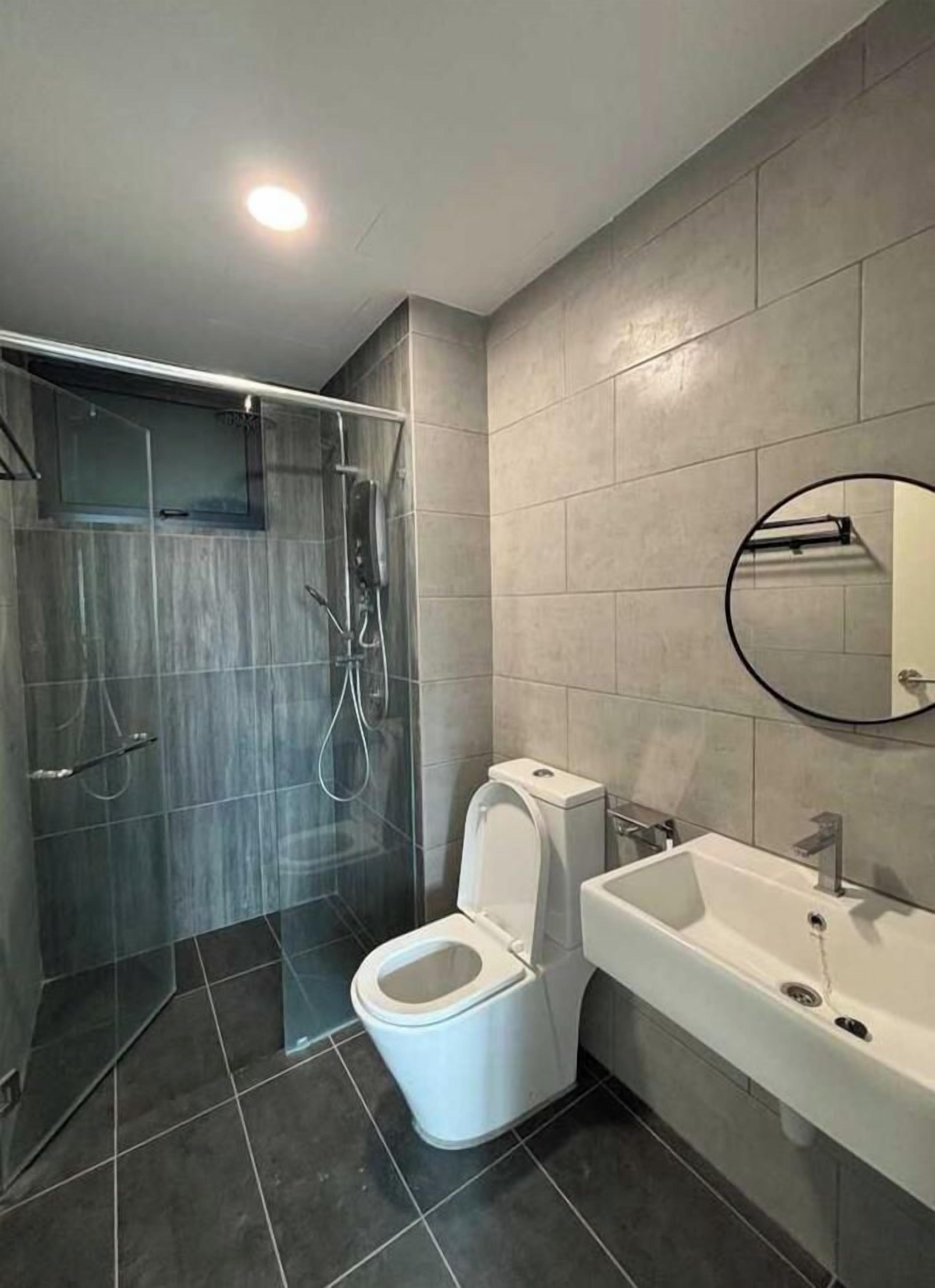 A modern bathroom with a glass-enclosed shower, a toilet, and a sink with a mirror.