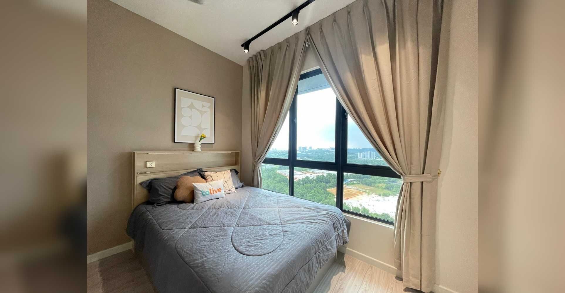Een slaapkamer met een groot raam, een bed met een grijze deken, een nachtkastje en een lijst met een afbeelding aan de muur.