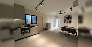 A modern kitchen with a built-in oven, a dining area with a table and chairs, and a ceiling fan.