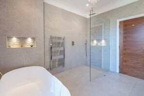 A modern bathroom with a glass shower enclosure, a built-in towel rack, and a wooden door. - Stunning 4BDR House with Garden in Brixton (Greater London)