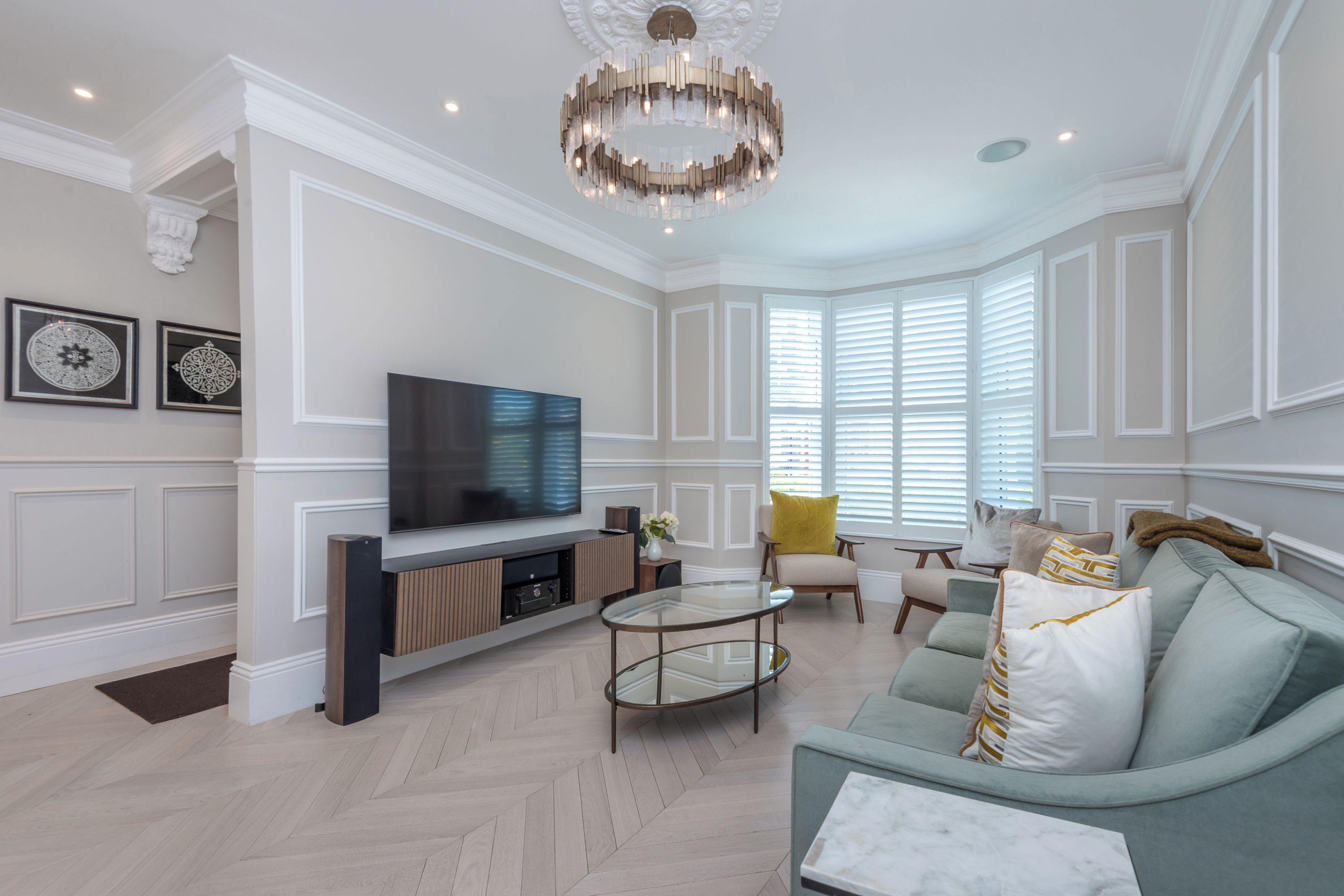A living room with a flat-screen TV, a glass coffee table, and a sofa with cushions.