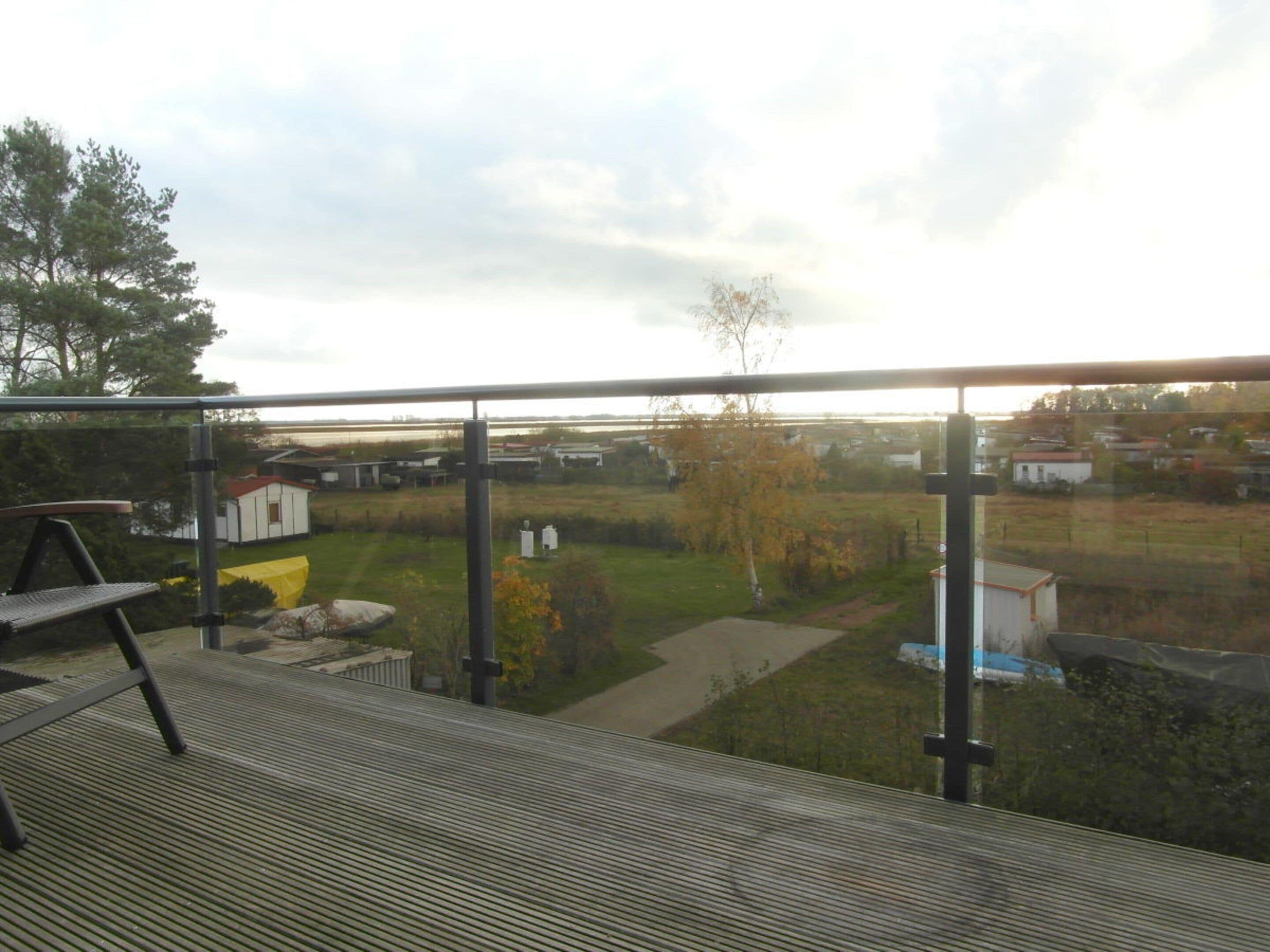 Un balcon donnant sur un espace verdoyant et sur des bâtiments situés au loin.