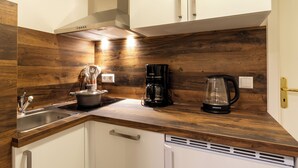 Eine Küche mit Holzausziehtischen, einer Kaffeemaschine, einem Wasserkocher und einem Topf auf dem Herd.
