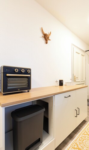 A kitchen with a built-in oven, a trash bin, and a wall-mounted decorative item.