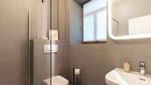 Ein modernes Badezimmer mit Toilette, Waschbecken und Duschbereich.