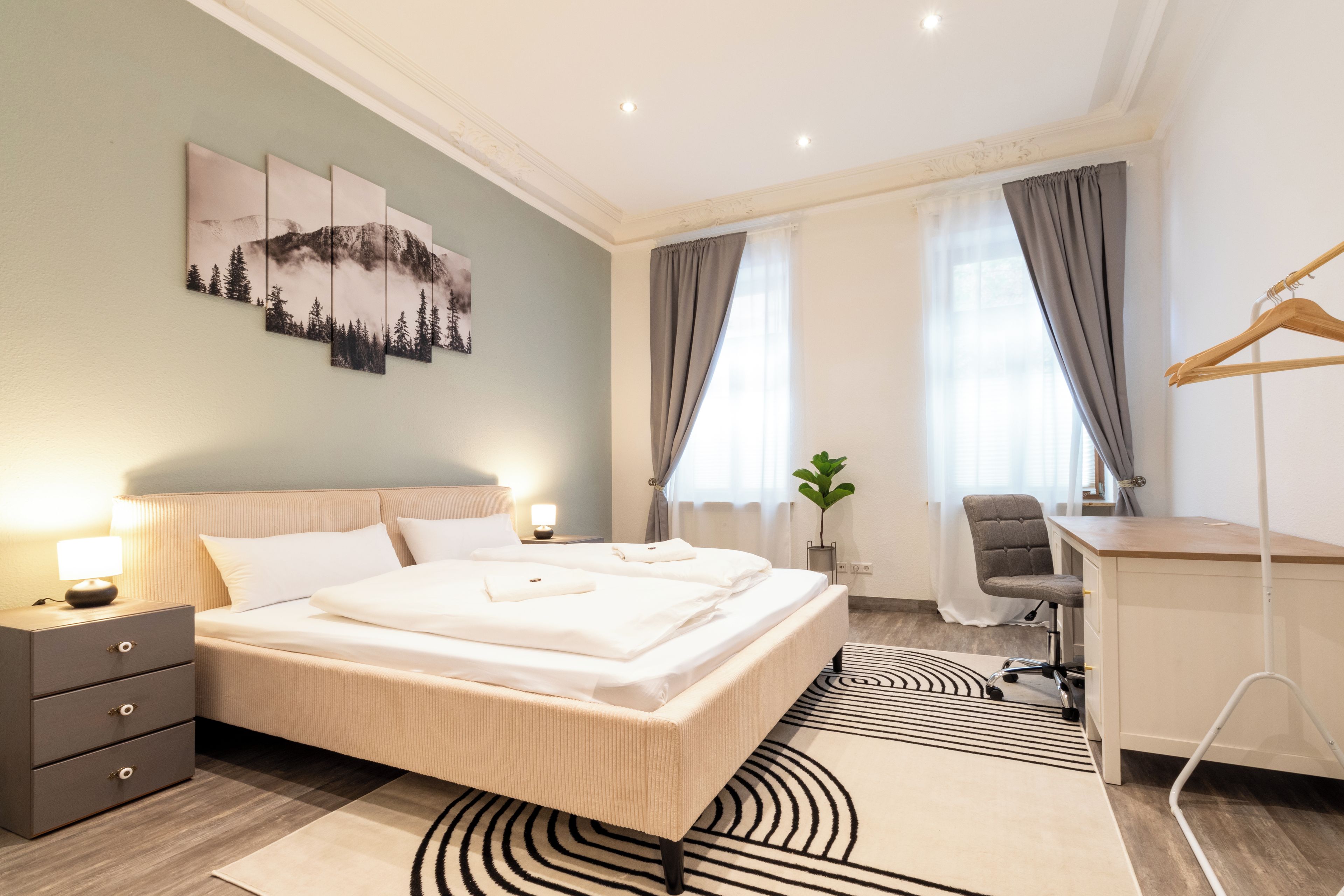 Ein modernes Hotelzimmer mit einem großen Bett, Nachttischen, einem Schreibtisch und einem Stuhl.