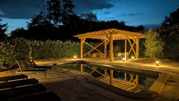 A wooden gazebo with string lights, a pool, and outdoor seating. - Villa 'Piscine 9pers SaôneBeaujolais' with Private Pool, Shared Terrace and Wi-Fi (Montmerle-sur-Saône)