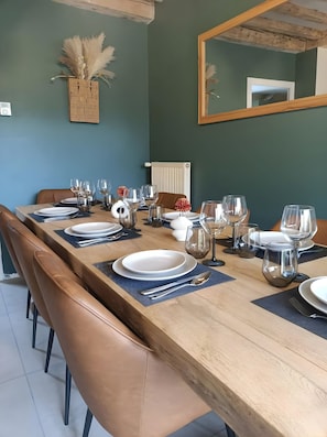 Uma sala de jantar com uma mesa de madeira comprida posta para refeição, rodeada por cadeiras de couro.