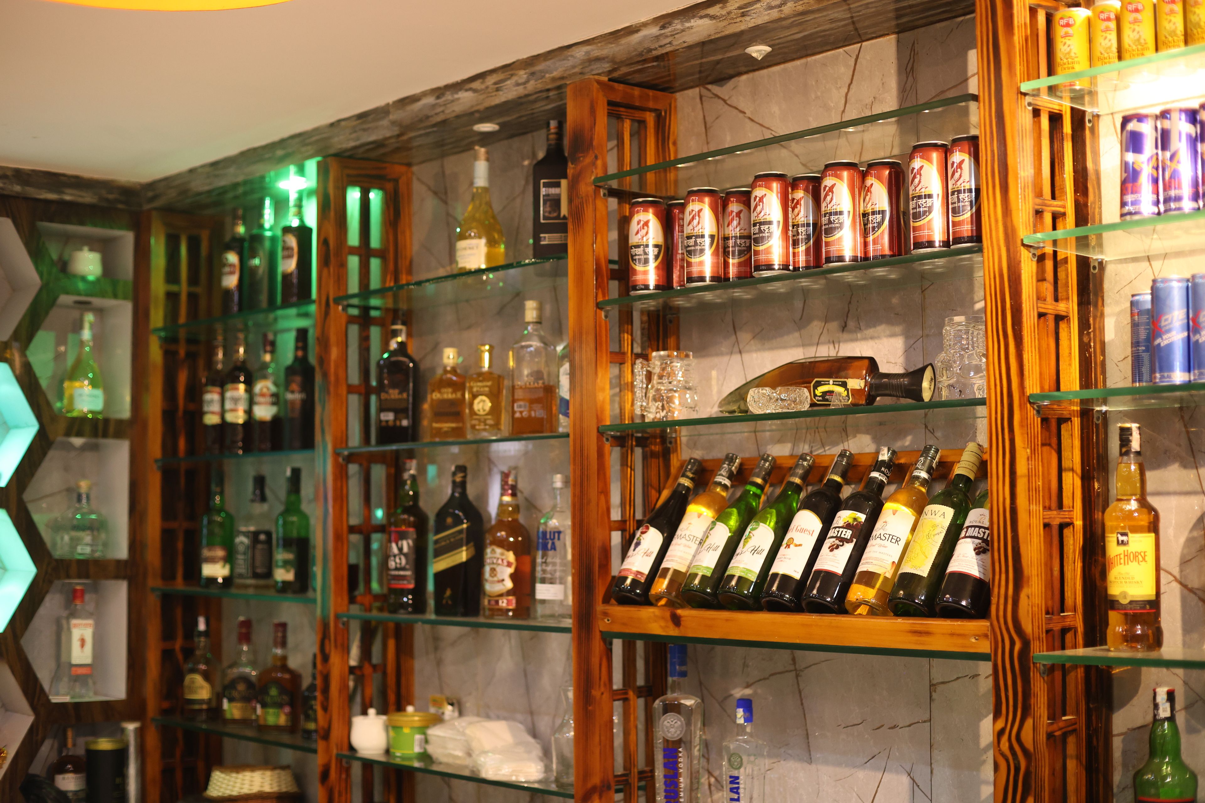 A bar area with shelves stocked with various liquor bottles and canned beverages.