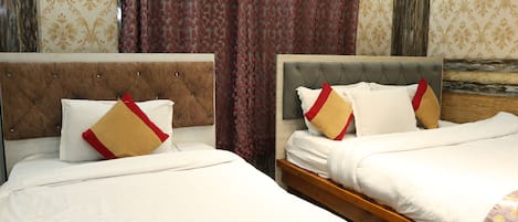 Habitación de hotel con dos camas, cada una con cabecera, mesita de noche de madera y pared con diseño.