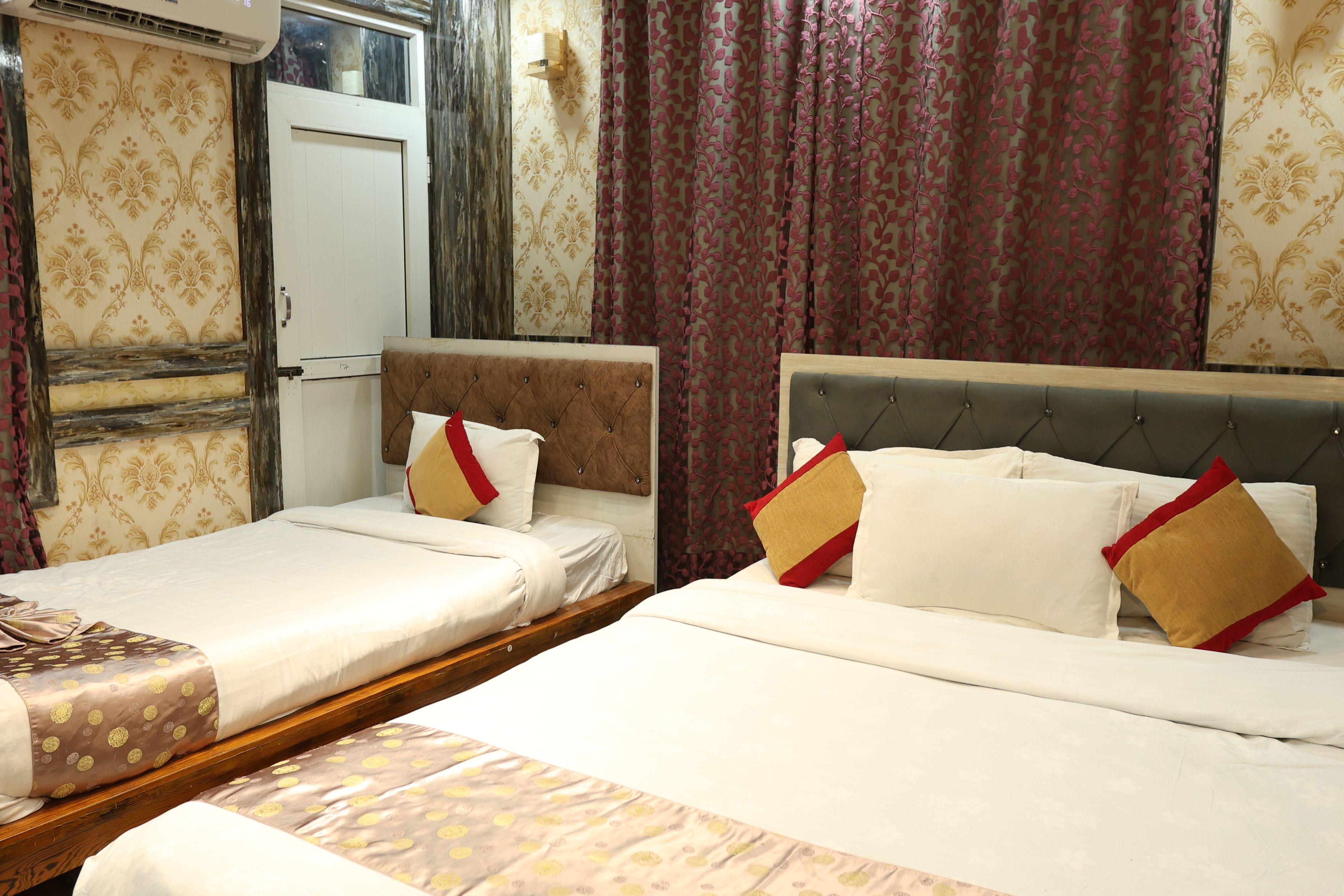 A hotel room with two single beds, a wooden headboard, and a large mirror.