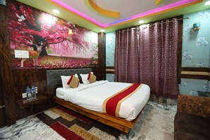 Un dormitorio con una cama grande, una mesita de noche, una lámpara de pared y un cuadro decorativo.