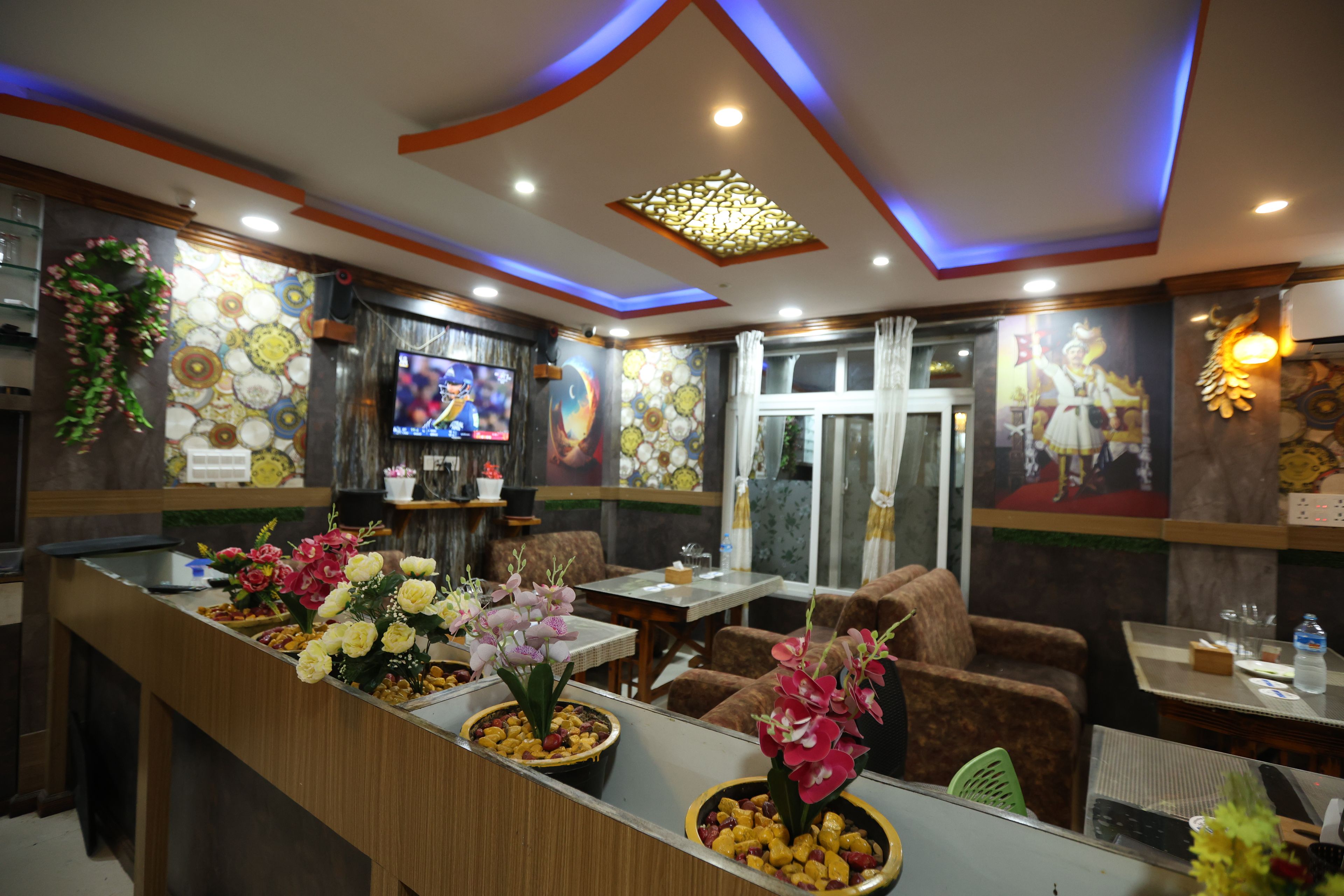 A restaurant interior with a counter, seating, decorative wall art, and a television.
