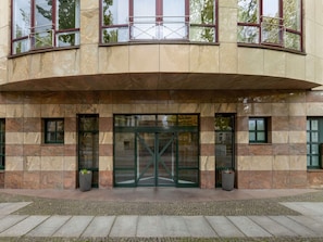 Un edificio con entrada curva, amplias puertas de cristal y fachada de piedra.