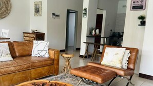 Uma sala de estar com sofá de couro marrom, mesa de centro de madeira e tapete estampado.