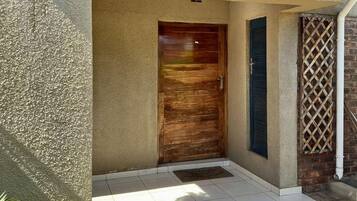 A residential entrance with a number '27' on the wall, a wooden door, and a small porch area.