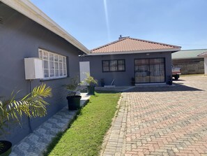 A residential property with a paved driveway, a small house with a tiled roof, and a well-maintained lawn. - Newly Renovated 4 Bedroom Guesthouse - 2389 (Harare)