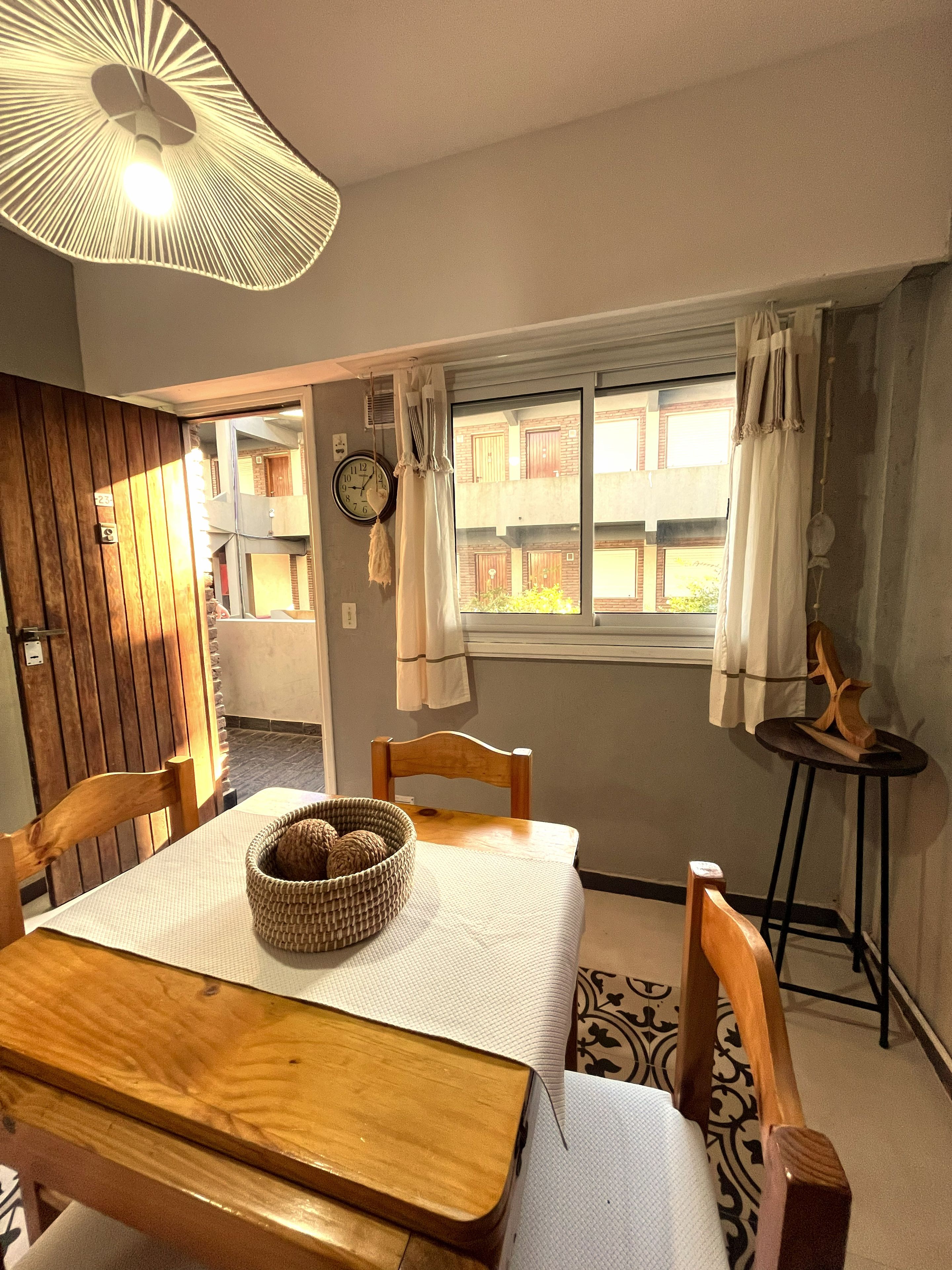 Un coin repas avec une table en bois, des chaises, un panier en osier et un luminaire suspendu.