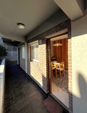 A corridor with a brick wall, a door leading to a room with a patterned floor, and a ceiling light. - Dept. "Caracolas" | Half a Block from the Beach - Ayres del Bosque Lodging (Valeria del Mar)