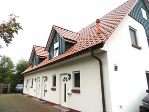 Ein zweistöckiges Haus mit rotem Ziegeldach, weißen Außenwänden und einer Auffahrt aus Ziegelsteinen.