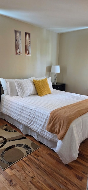 A bedroom with a bed, pillows, a bedside table with a lamp, and a rug. - Spacious 3BR-2BA Upstairs Unit near NYC Train & Bus - Driveway Parking Included (Roselle)