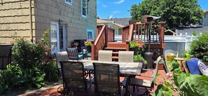 A patio with a table and chairs, surrounded by potted plants and a wooden deck.