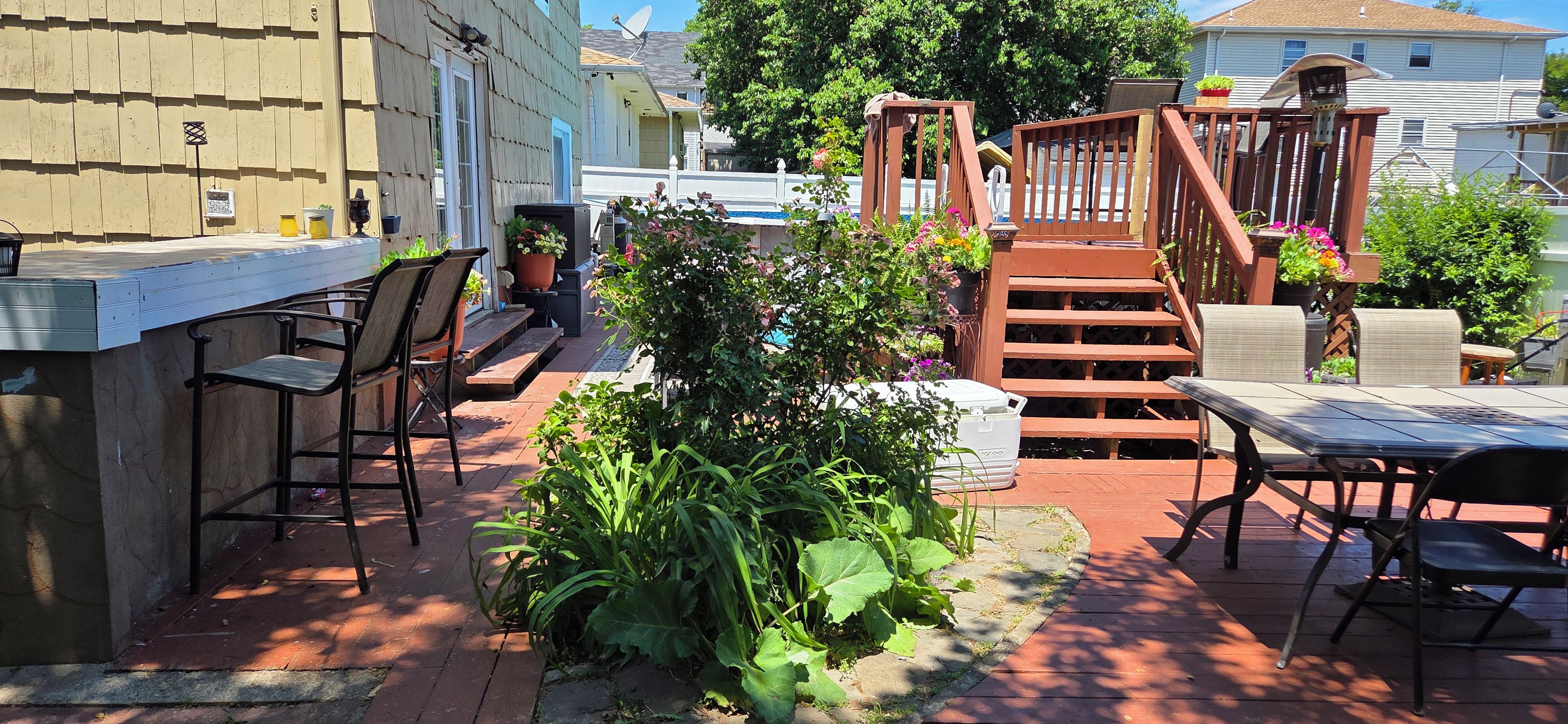 Une terrasse extérieure dotée d’un bar, de coins salon et d’un escalier en bois.