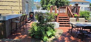 Un patio exterior con zona de bar, asientos y una escalera de madera.