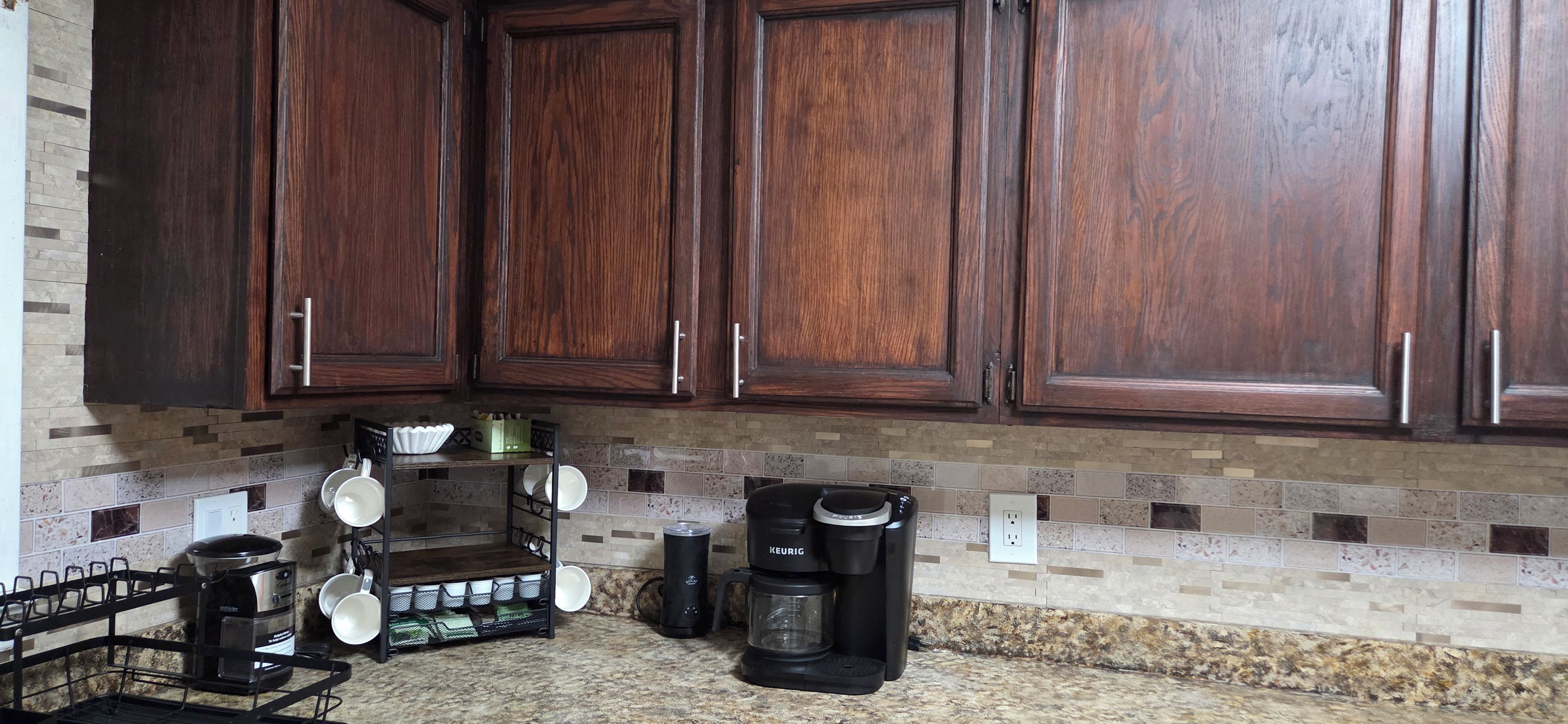 Una cocina con armarios de madera oscura, una cafetera y un hervidor sobre la encimera.