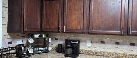 Una cocina con armarios de madera oscura, una cafetera y un hervidor sobre la encimera.