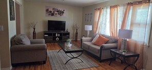 A living room with a sofa, armchair, TV, and a coffee table. - Spacious 3BR-2BA Upstairs Unit near NYC Train & Bus - Driveway Parking Included (Roselle)