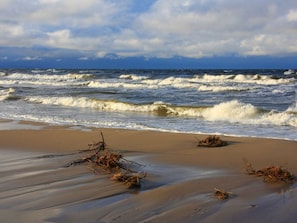 A beach with waves and seaweed on the sand. - Holiday Home With 1 Bedroom (Loddin)