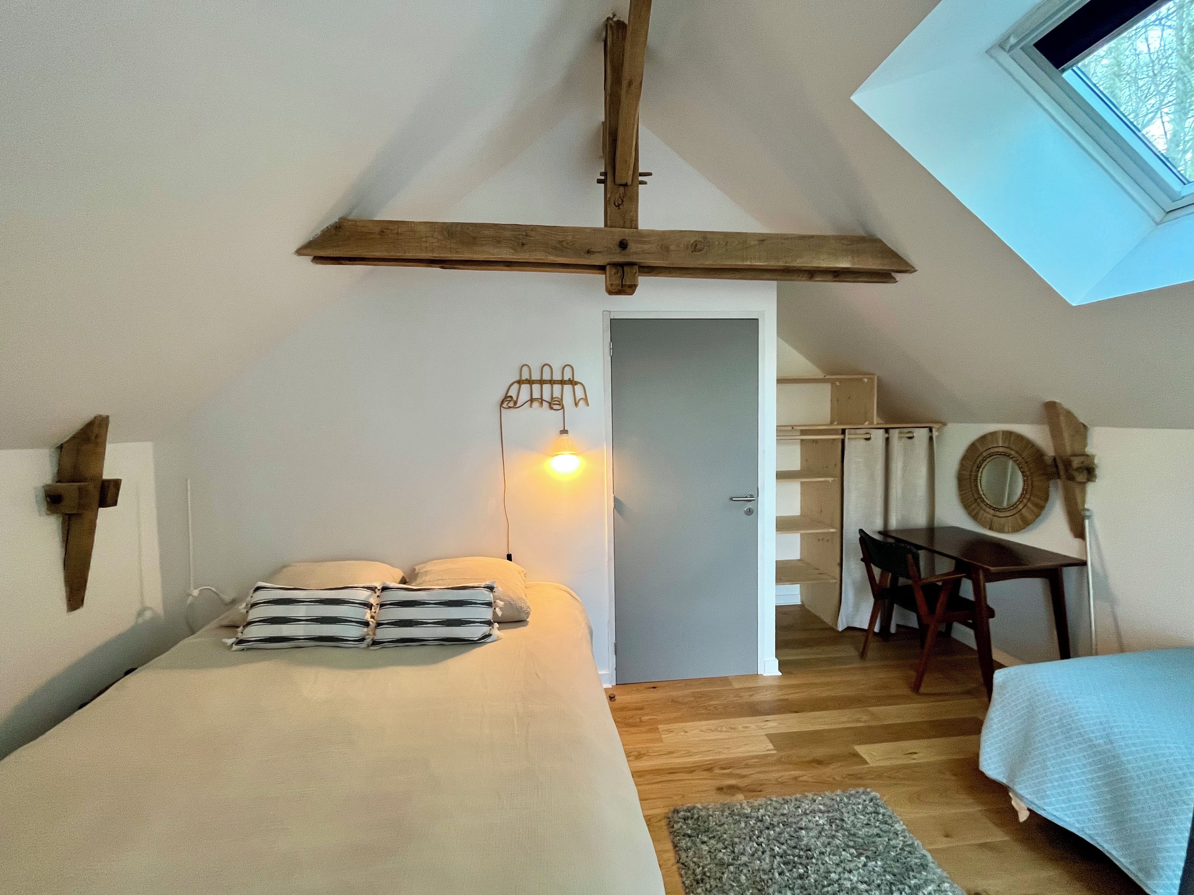 Une chambre à coucher avec un lit, un bureau, une chaise, une fenêtre et une porte.